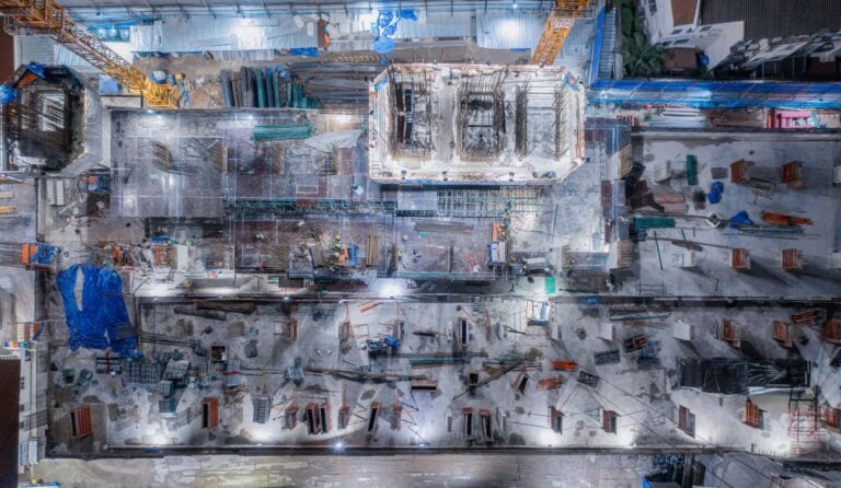 After Hours Tracking, Construction site aerial view with workers and equipment.