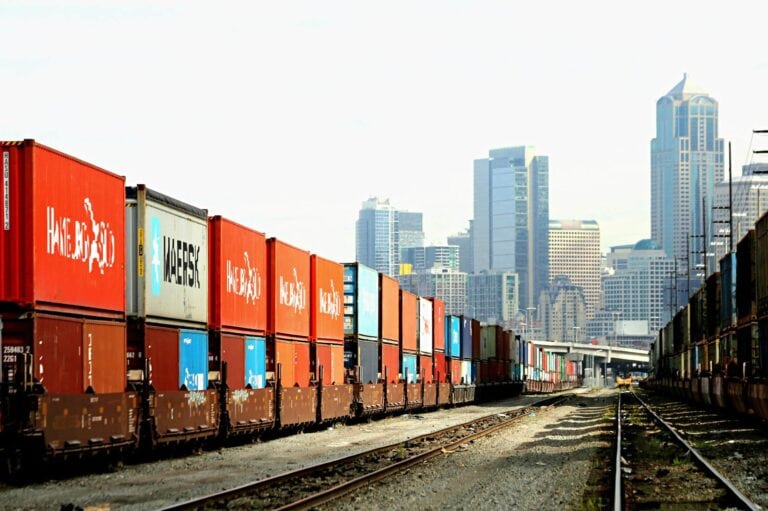 Movement Based Tracking, Cargo train with shipping containers and a city skyline in the background, highlighting freight tracking and logistics solutions.