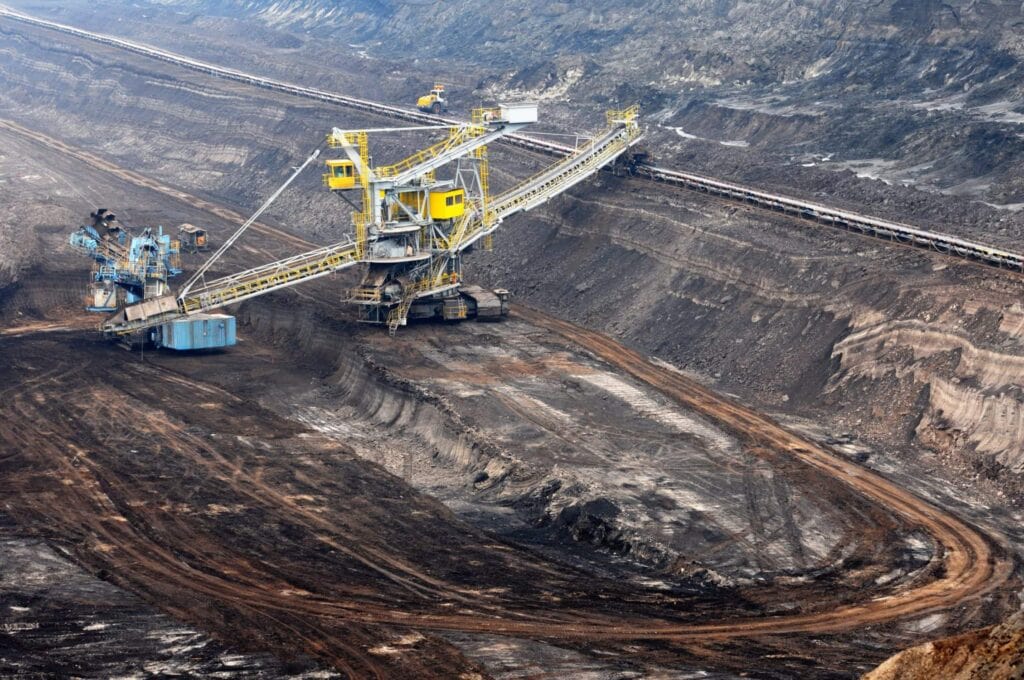 Remote Worker Monitoring, Drone view of an open-pit mining operation with heavy equipment and GPS tracking technology.